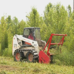 A bobcat loading a dump truck with mulch.